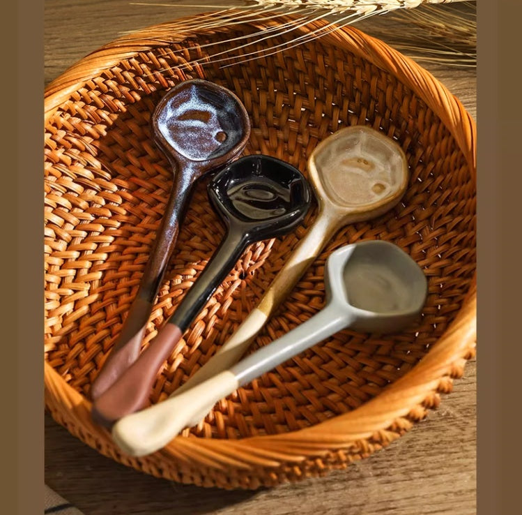 Four glazed ceramic spoons with long handles resting in a woven rattan basket