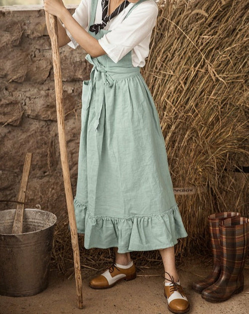 Side view of the sage green cotton-linen apron with long waist ties and ruffled hem