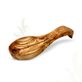Carved natural olive wood spoon rest beside a stovetop