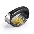 Curved stainless steel rocking garlic press on a kitchen counter